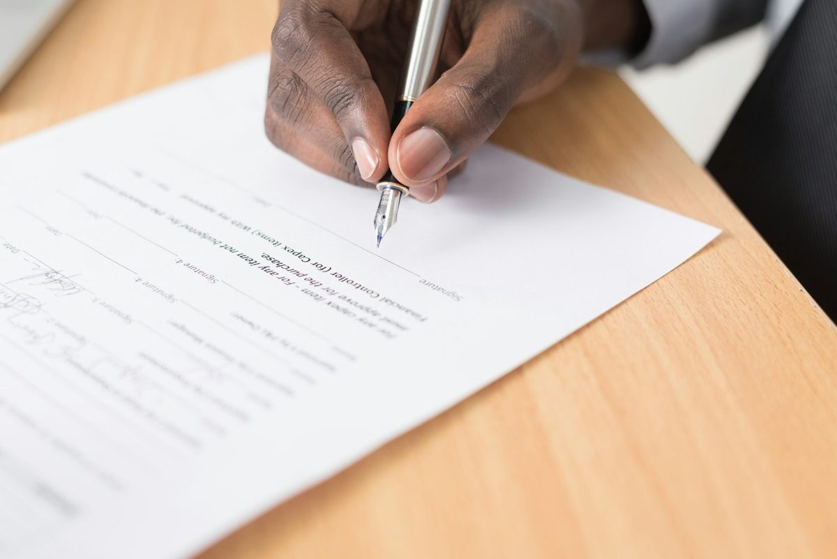Mano firmando un contrato con una pluma