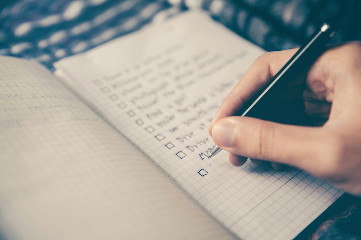 Mano escribiendo una lista con casillas en un cuaderno