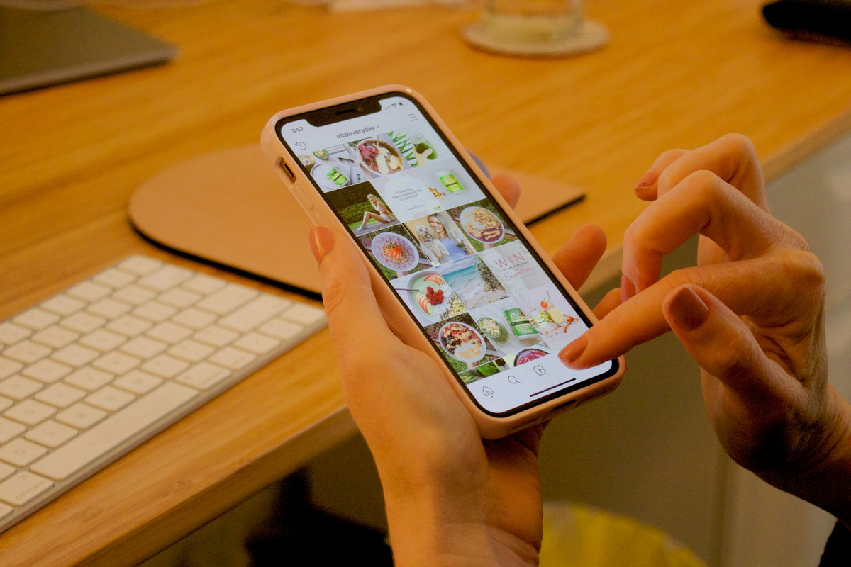 Manos con un móvil que enseña una cuadrícula de fotos de comida