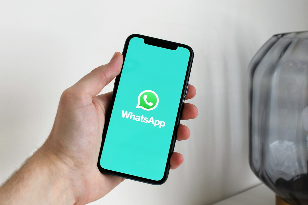 Mano con un móvil que enseña la pantalla de inicio de WhatsApp