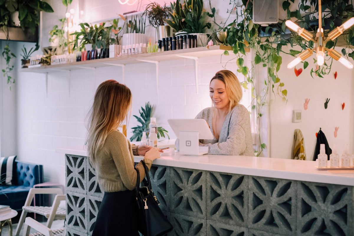 Clienta hablando con la recepcionista en el mostrador de un negocio