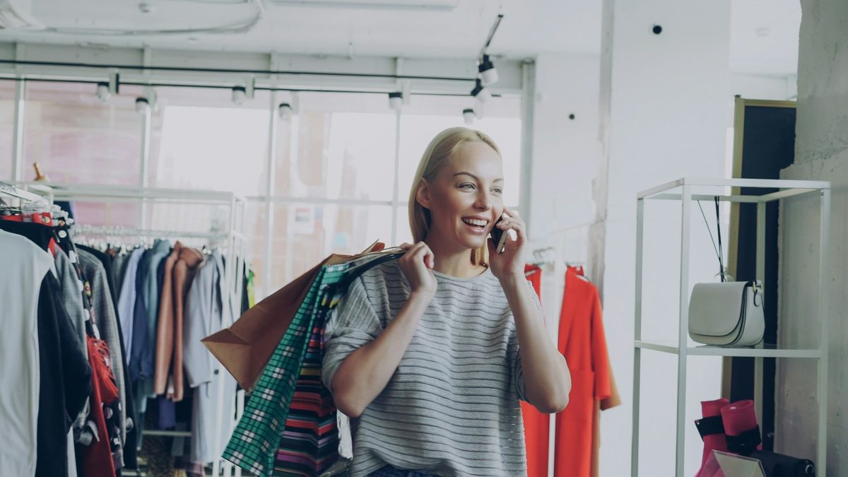 Dueña de una tienda de ropa hablando por teléfono y sonriendo