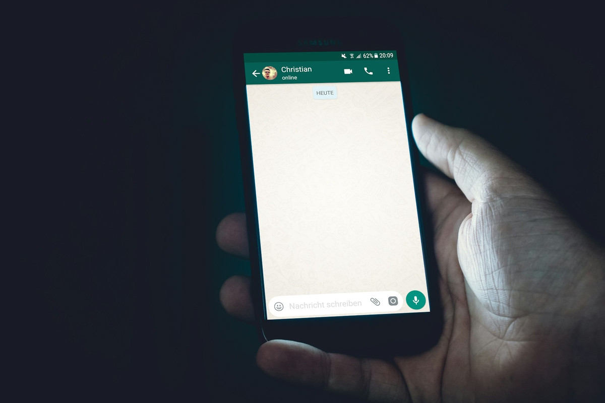 Mano con un móvil que enseña una conversación de WhatsApp