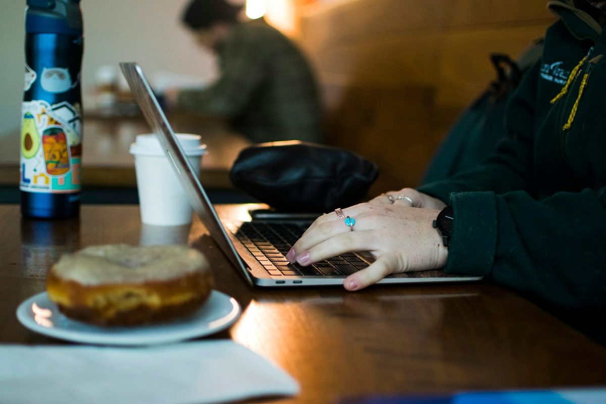 Persona trabajando con un portátil en la mesa de una cafetería