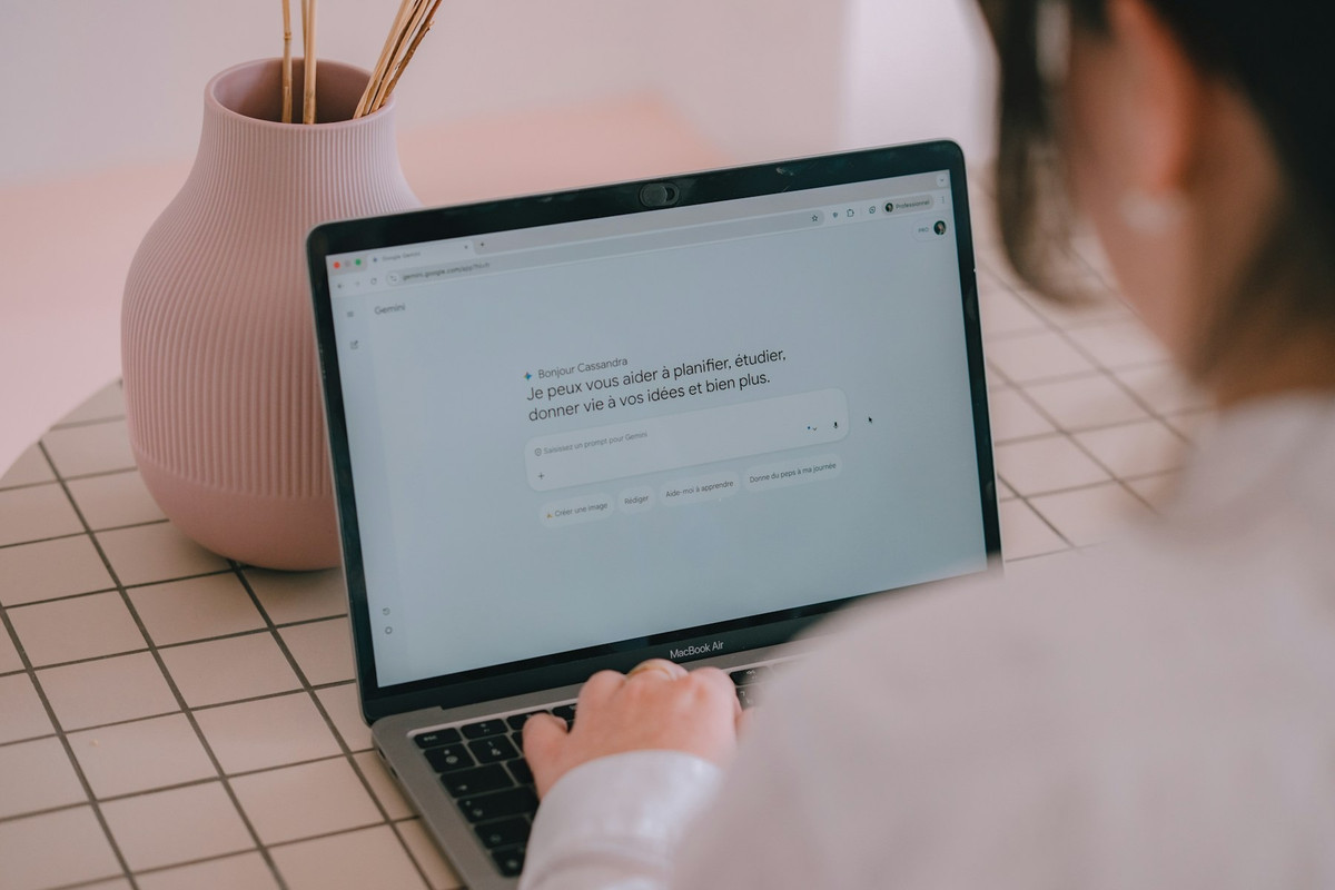 Mujer escribiendo una pregunta a un asistente de inteligencia artificial en un portátil
