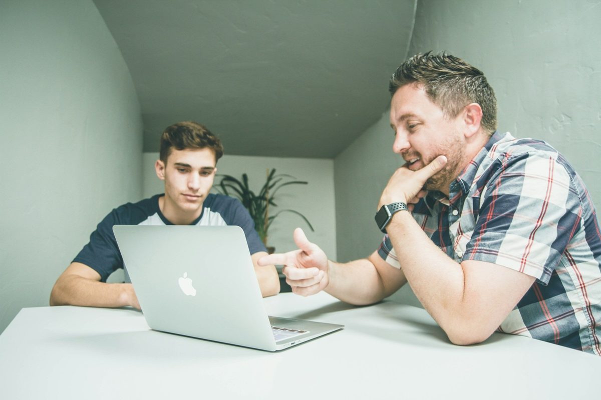 Mentor explicando algo a un joven delante de un portátil