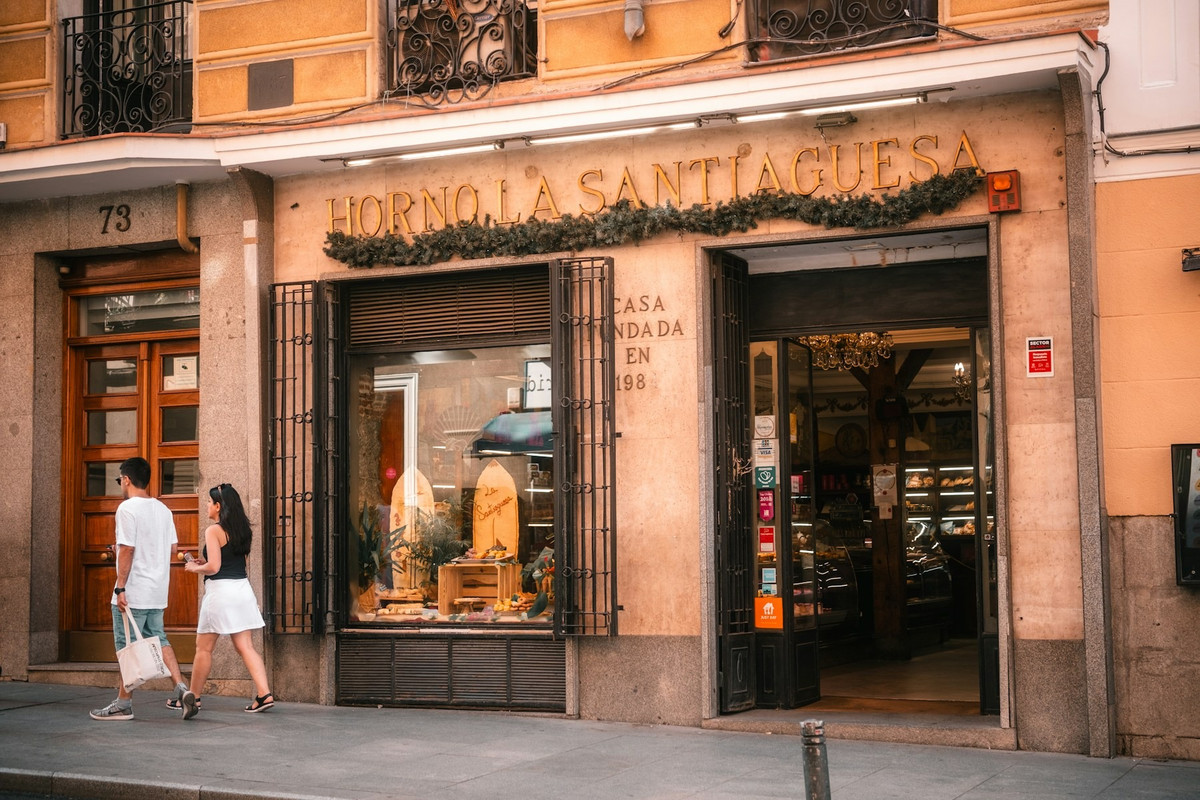 Fachada de una panadería de barrio con gente pasando por delante