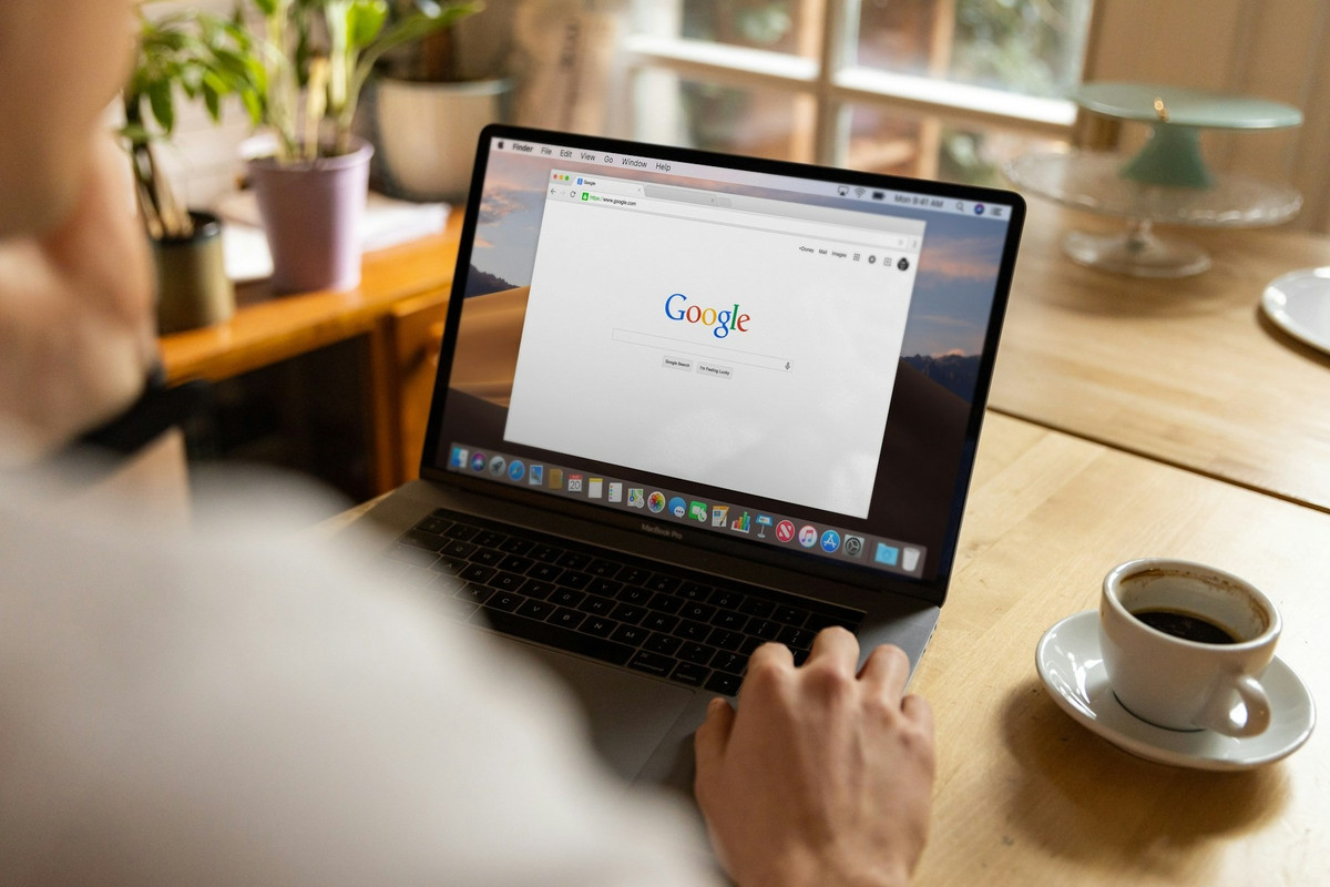 Persona buscando en Google desde un portátil en una cafetería