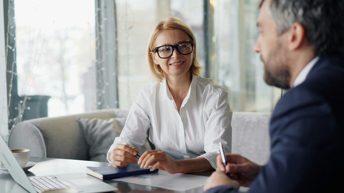 Abogada con gafas atendiendo a un cliente en la mesa de su despacho