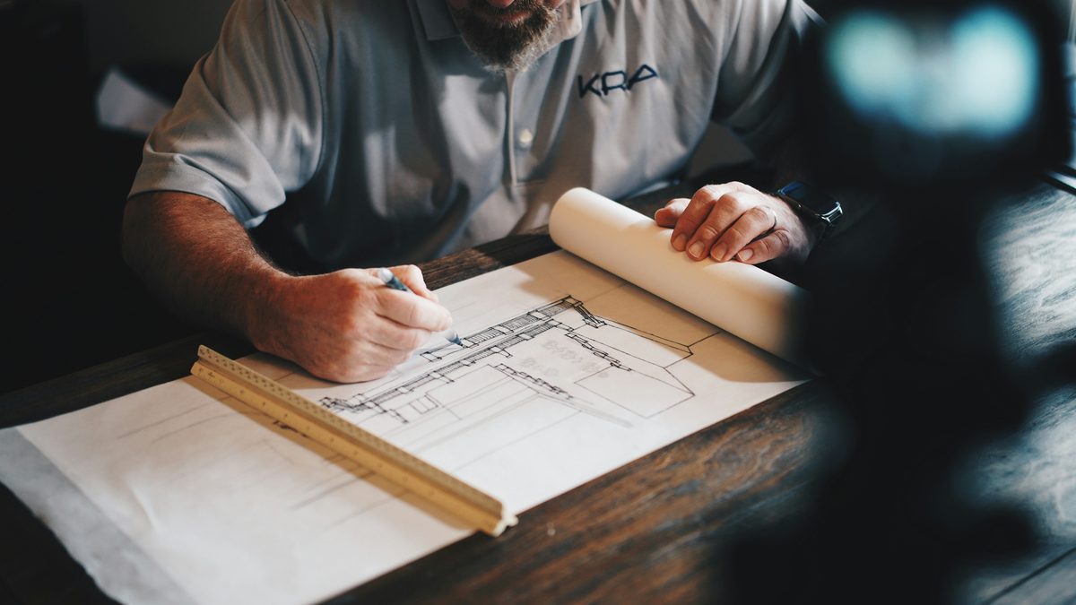 Arquitecto dibujando un plano a lápiz sobre la mesa de su estudio