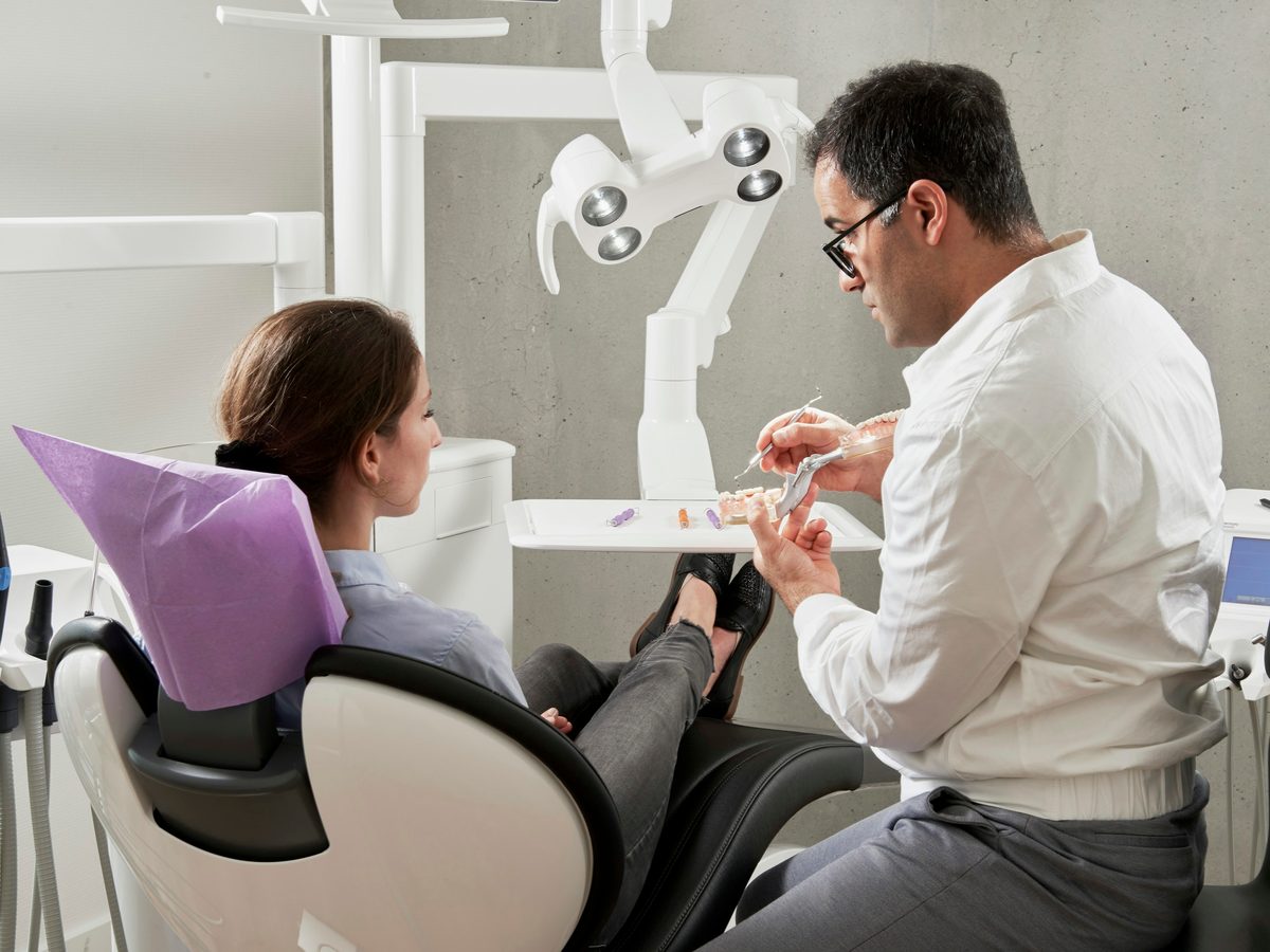 Dentista hablando con una paciente sentada en el sillón de la clínica