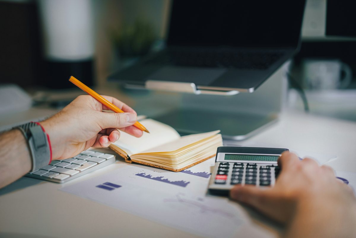 Manos repasando unas cuentas con calculadora y libreta en una mesa