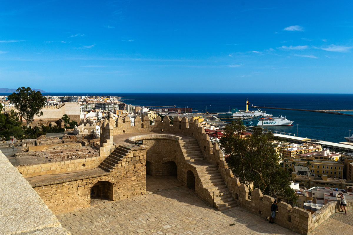 Las murallas de la Alcazaba de Almería con el puerto, un ferri y el mar al fondo, en un día despejado
