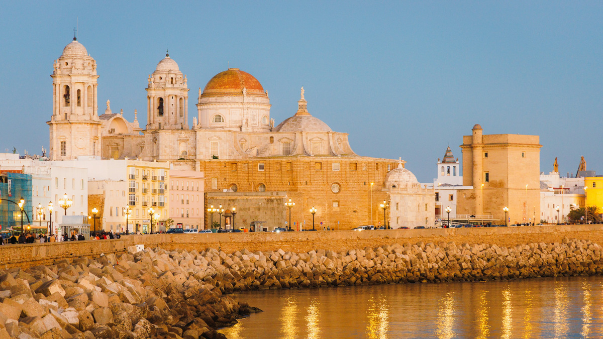 La catedral de Cádiz, con su cúpula dorada y sus dos torres, vista desde el paseo marítimo al atardecer