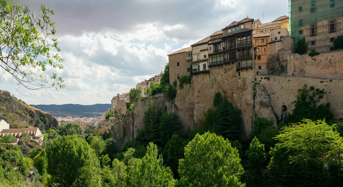 Panorámica de las Casas Colgadas de Cuenca sobre la roca de la hoz, con árboles en primer término