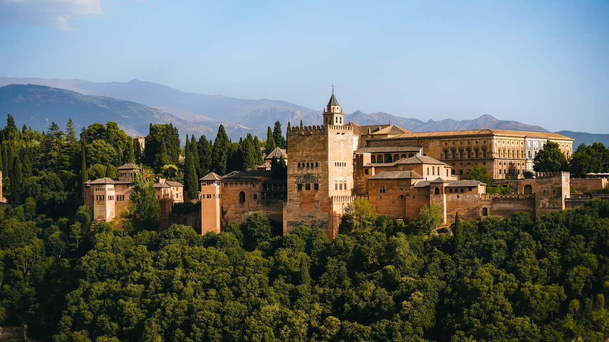 La Alhambra de Granada sobre la arboleda, con Sierra Nevada al fondo