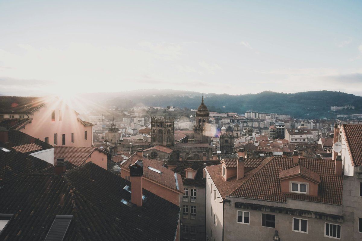 Vista de los tejados del casco viejo de Ourense con las torres de la catedral en el centro y los montes al fondo