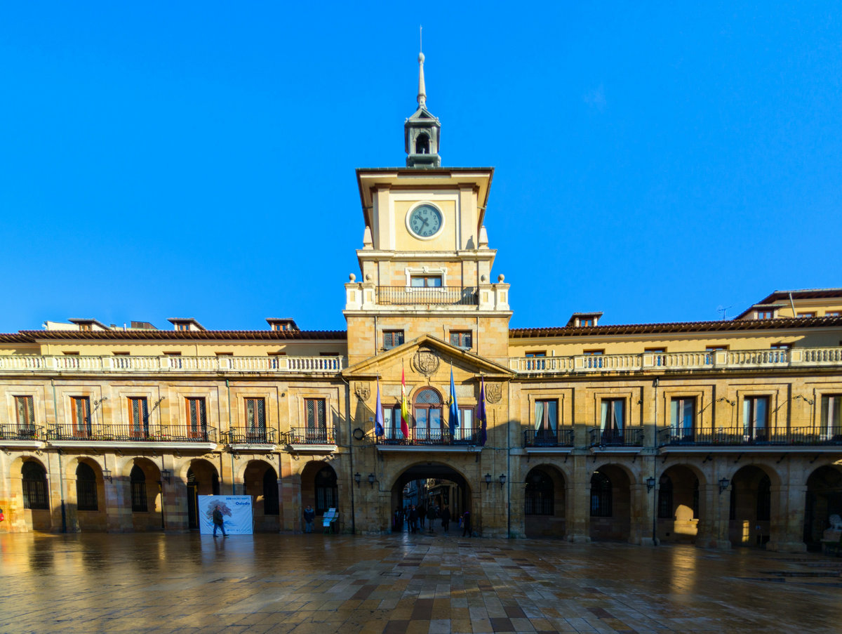 La fachada del Ayuntamiento de Oviedo, con su torre del reloj y los soportales, en un día despejado