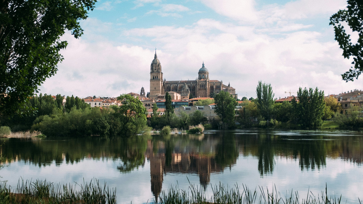 La catedral de Salamanca reflejada en el río Tormes, entre los árboles de la orilla